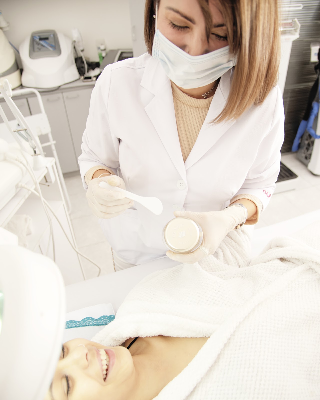 Close-up elegant aesthetic skincare facial treatment in a luxury dermatology spa clinic, female client with glowing radiant healthy skin receiving gentle treatment, warm soft lighting, neutral tones, editorial aesthetic photography